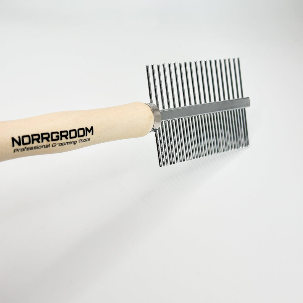 Professional groomer using NorrGroom dual-sided dog comb with wooden handle during grooming session

