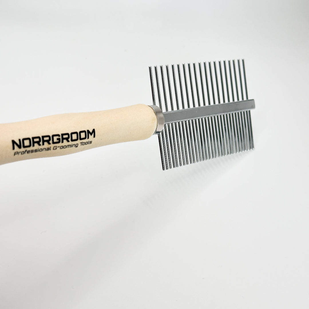 Professional groomer using NorrGroom dual-sided dog comb with wooden handle during grooming session


